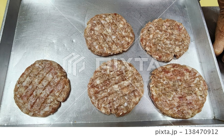 Five Raw Beef Burger Patties on a Metal Baking Sheet Tray in a Commercial Kitchen 138470912