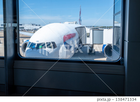 British airways boeing 777 airplane parked at an airport gate, connected to the jet bridge and waiting for passengers before departing for an international flight 138471334