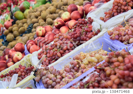 Fruit display at a market with various types of grapes, apples, and kiwis in the daytime 138471468