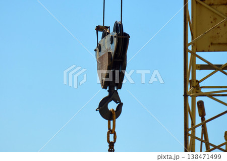 A construction crane stands tall at a building site. It lifts materials into the air while workers move around A construction crane stands tall at a building site. It lifts materials into the air while workers move around 138471499
