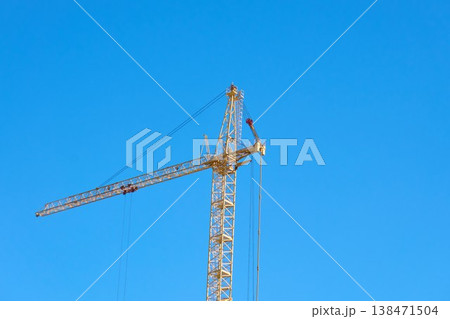 Construction crane stands tall against the blue sky during the day in an urban area 138471504