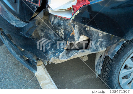 A car rear bumper shows signs of damage with a cracked and dented area A car rear bumper shows signs of damage with a cracked and dented area 138471507