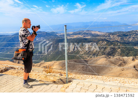 Travel photographer man with professional camera taking photos of on a top of Tahtali mountain near Kemer, Antalya Province in Turkey Travel photographer man with professional camera taking photos of on a top of Tahtali mountain near Kemer, Antalya Province in Turkey 138471592