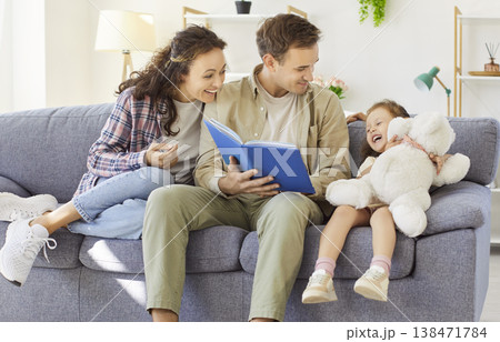 Happy family reading a storybook together on the sofa at home, playful moments 138471784