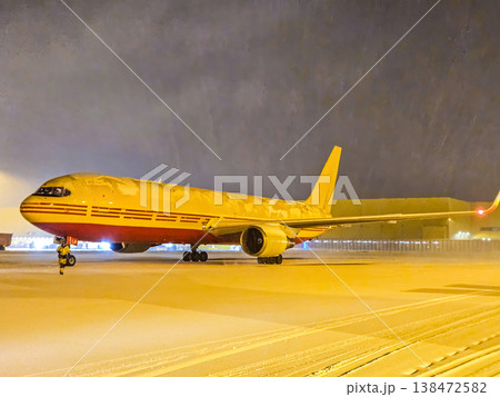 DHL cargo plane on a snowy airport runway at night. Global logistics and air freight transportation in winter weather. 138472582