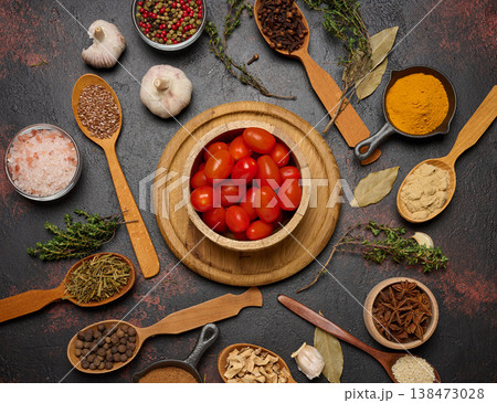 Cherry tomatoes in a wooden bowl and various spices on a dark table, top view Cherry tomatoes in a wooden bowl and various spices on a dark table, top view 138473028