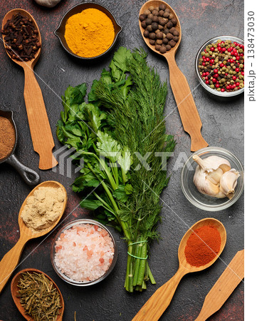 Spices, herbs, and garlic on a dark background. Turmeric, paprika, pepper, cloves, ginger, and salt in bowls and spoons. Spices, herbs, and garlic on a dark background. Turmeric, paprika, pepper, cloves, ginger, and salt in bowls and spoons. 138473030