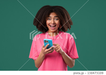 Shocked african woman staring smartphone on green studio with open mouth.Amazed Shocked african woman staring smartphone on green studio with open mouth.Amazed 138473109