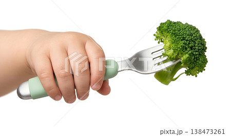Tiny baby hand grasping a toddler fork with a small piece of steamed broccoli, representing first vegetables, self-feeding, and healthy eating 138473261