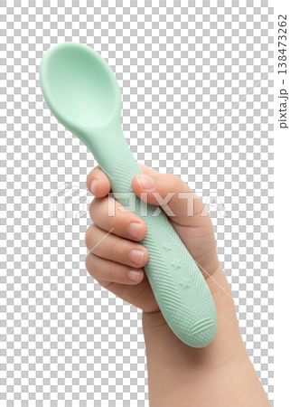 Toddler's small hand gripping a soft green silicone baby spoon, representing self-feeding practice, fine motor skills, and mealtime independence Toddler's small hand gripping a soft green silicone baby spoon, representing self-feeding practice, fine motor skills, and mealtime independence 138473262