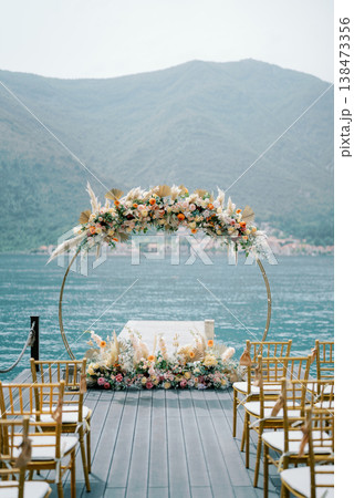 Elegant Arch Adorned With Flowers Overlooking Peaceful Mountain Lake Elegant Arch Adorned With Flowers Overlooking Peaceful Mountain Lake 138473356