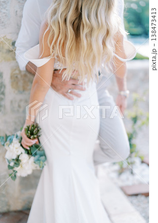 Bride And Groom Hold Each Other Closely In Beautiful Outdoor Setting 138473413