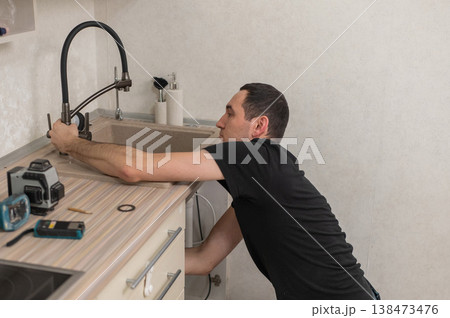 A plumber is replacing a faucet in the kitchen. A plumber is replacing a faucet in the kitchen. 138473476