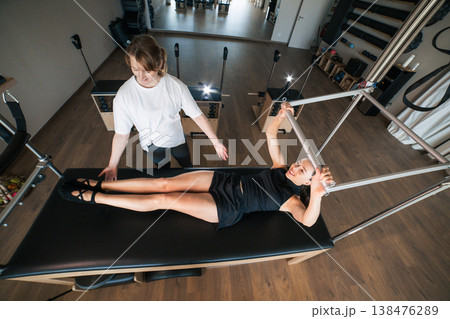 Woman exercising pilates with personal trainer guidance Woman exercising pilates with personal trainer guidance 138476289