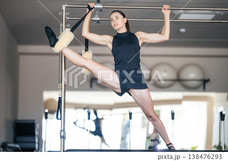 Woman exercising flexibility on pilates cadillac machine Woman exercising flexibility on pilates cadillac machine 138476293