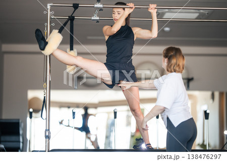 Woman stretching leg on pilates cadillac during fitness class Woman stretching leg on pilates cadillac during fitness class 138476297