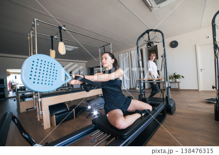 Woman exercising pilates reformer with paddle training equipment Woman exercising pilates reformer with paddle training equipment 138476315