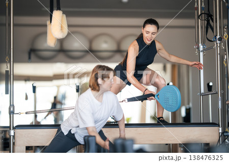 Pilates instructor guiding woman with reformer exercise Pilates instructor guiding woman with reformer exercise 138476325