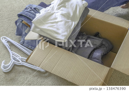 Packing clothes into cardboard box at home 138476390