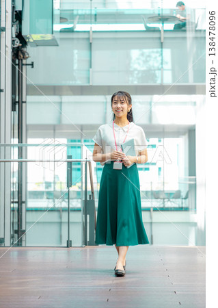 手帳を持って廊下を歩く若い女性 138478096