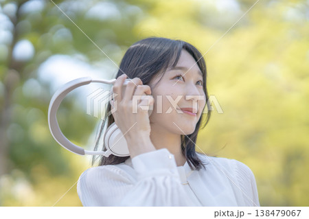 自然の中でワイヤレスヘッドホンを使用する若い女性 屋外 リフレッシュ 138479067