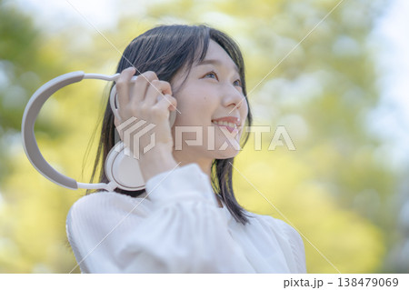 自然の中でワイヤレスヘッドホンを使用する若い女性 屋外 リフレッシュ 自然の中でワイヤレスヘッドホンを使用する若い女性 屋外 リフレッシュ 138479069