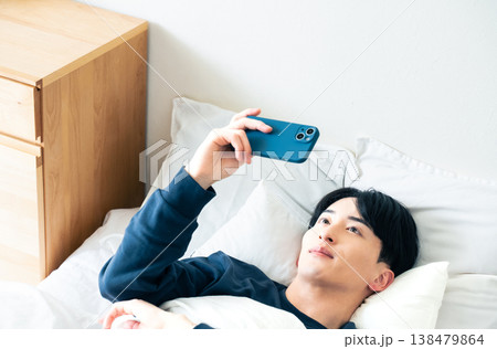 ベッドでスマホを見る若い男性 138479864