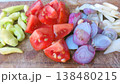 A vibrant display of fresh, chopped vegetables including red tomatoes, purple shallots, white garlic, and green chilies, neatly arranged on a rustic wooden cutting board, ready for cooking a healthy 138480215
