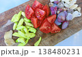 Vibrant selection of fresh, raw cooking ingredients on a rustic wooden board. Features chopped tomatoes, green chili peppers, peeled garlic cloves, shallots, and ginger. 138480231