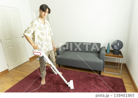 Young teen boy vacuuming floor with vacuum cleaner in living room. Young teen boy vacuuming floor with vacuum cleaner in living room. 138481865