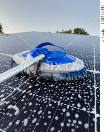 Cleaning a solar panel on a rooftop during clear weather Cleaning a solar panel on a rooftop during clear weather 138482446