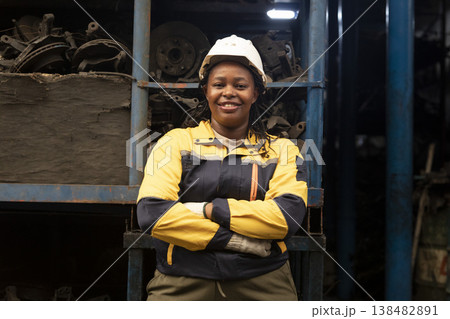 Technician African black women worker standing and smile in garage scrap yard old car part warehouse. Technician African black women worker standing and smile in garage scrap yard old car part warehouse. 138482891