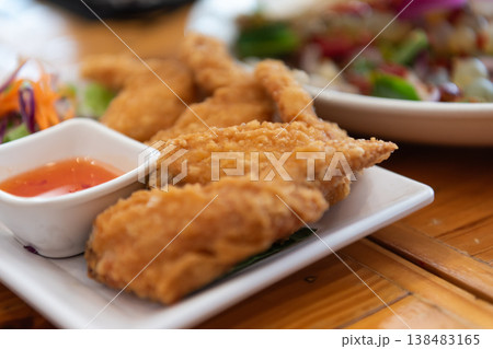 Crispy fried chicken served with dipping sauce on plate golden texture crunchy surface and savory flavor popular meal in casual dining setting Crispy fried chicken served with dipping sauce on plate golden texture crunchy surface and savory flavor popular meal in casual dining setting 138483165