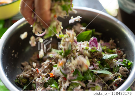 spicy mackerel salad with fresh herbs onion chili and lime being tossed by hand in metal bowl thai traditional dish bold flavor fresh ingredients and vibrant texture spicy mackerel salad with fresh herbs onion chili and lime being tossed by hand in metal bowl thai traditional dish bold flavor fresh ingredients and vibrant texture 138483179