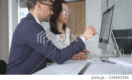 Architects collaborating on building design showing blueprints and project plans on computer screen in office. Business and architecture concept 138483548
