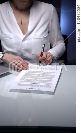 Businesswoman signing a contract late in the office, closing a deal, or completing legal paperwork at deep night. Audit and overworking concepts Businesswoman signing a contract late in the office, closing a deal, or completing legal paperwork at deep night. Audit and overworking concepts 138483584