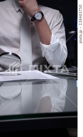 Person examining a document using a magnifying glass, focusing on fine print and terms in a legal agreement, working late. Audit and overworking concepts 138483750