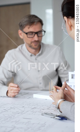 Architects and designer planning a modern house building project, collaborating on construction blueprints and architectural model in a professional office, close up Architects and designer planning a modern house building project, collaborating on construction blueprints and architectural model in a professional office, close up 138483803