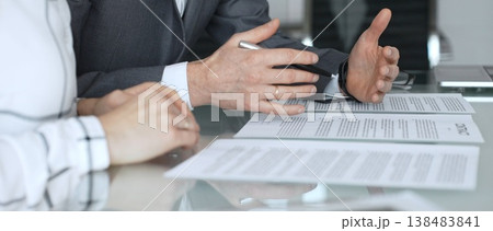 Business executive hands gesturing over contract on glass table during formal office meeting negotiating legal agreement terms. Business people concept Business executive hands gesturing over contract on glass table during formal office meeting negotiating legal agreement terms. Business people concept 138483841