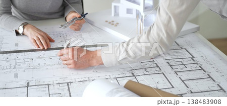 Stressed female architect analyzing blueprints and architectural model, discussing new project designs and construction plans with a colleague during a frustrating meeting, close up 138483908