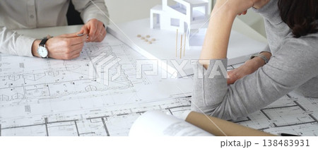Architects engaging in a design planning meeting, analyzing blueprints and a scale model, making precise measurements and discussing new construction project ideas, close up Architects engaging in a design planning meeting, analyzing blueprints and a scale model, making precise measurements and discussing new construction project ideas, close up 138483931