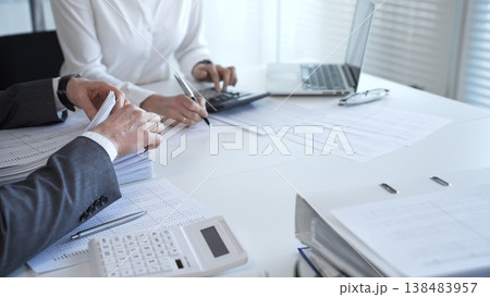 Accountants working together calculating taxes and auditing financial reports in a busy office setting. Audit and taxes in business Accountants working together calculating taxes and auditing financial reports in a busy office setting. Audit and taxes in business 138483957