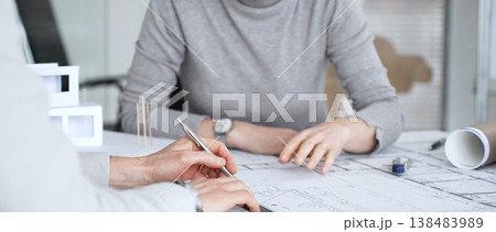 Architects discussing blueprints and a structural model on a desk, focusing on design concepts, project planning, and architectural development during an office meeting, close up Architects discussing blueprints and a structural model on a desk, focusing on design concepts, project planning, and architectural development during an office meeting, close up 138483989