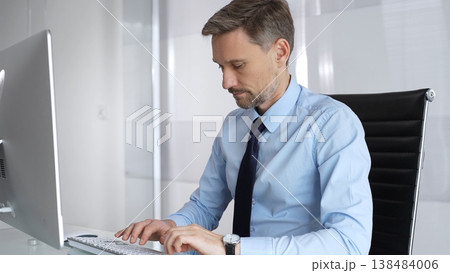 Thoughtful businessman working at his desk, intently looking at a computer screen while contemplating business solutions and actively developing new corporate strategies Thoughtful businessman working at his desk, intently looking at a computer screen while contemplating business solutions and actively developing new corporate strategies 138484006