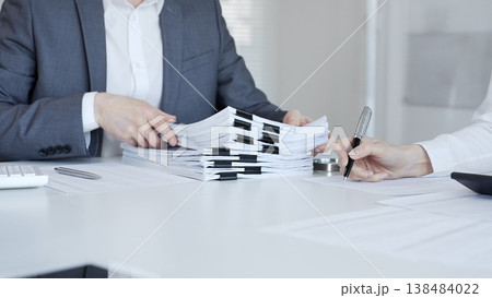 Business people preparing financial documents and signing reports at office desk, analyzing taxation data. Audit and taxes in business Business people preparing financial documents and signing reports at office desk, analyzing taxation data. Audit and taxes in business 138484022