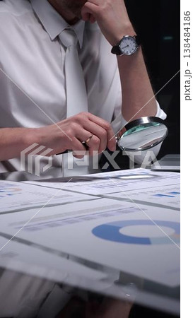 Businessman holding a magnifying glass and checking financial data, reviewing corporate audit reports, and analyzing various charts. Audit and taxes in business Businessman holding a magnifying glass and checking financial data, reviewing corporate audit reports, and analyzing various charts. Audit and taxes in business 138484186