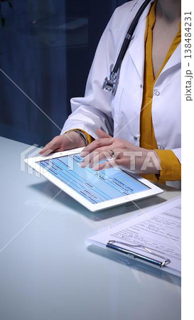 Doctor using digital tablet for remote patient data during an online consultation, managing electronic health records and telehealth services in a modern clinic Doctor using digital tablet for remote patient data during an online consultation, managing electronic health records and telehealth services in a modern clinic 138484231