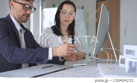 Architects collaborating on architectural project, discussing blueprints and design models on office table. Business and architecture concept Architects collaborating on architectural project, discussing blueprints and design models on office table. Business and architecture concept 138484232