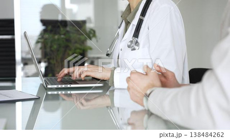 Doctor woman typing on laptop during medical consultation with patient, discussing healthcare technology and modern diagnostics. Medicine, health care and science concept Doctor woman typing on laptop during medical consultation with patient, discussing healthcare technology and modern diagnostics. Medicine, health care and science concept 138484262