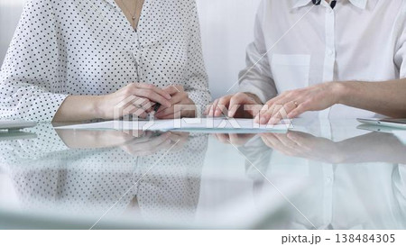 Business colleagues reviewing a contract, engaging in negotiations and strategic decision making in modern glass office, white casual dress style. Businesspeople concept Business colleagues reviewing a contract, engaging in negotiations and strategic decision making in modern glass office, white casual dress style. Businesspeople concept 138484305